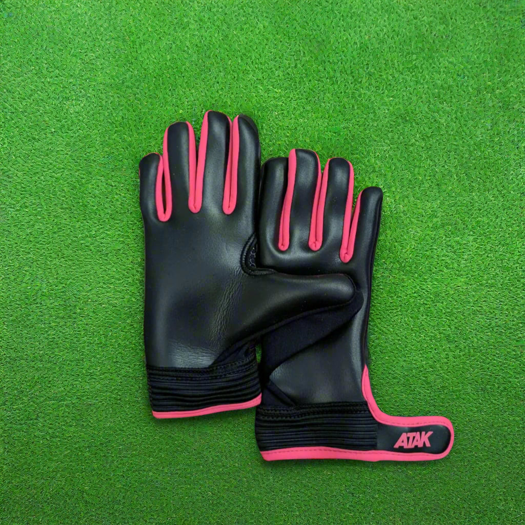 Black and pink ATAK air gloves on a green grass background