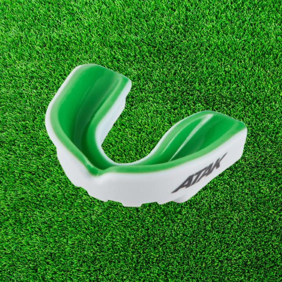 Green and white mouthguard on a green grass background