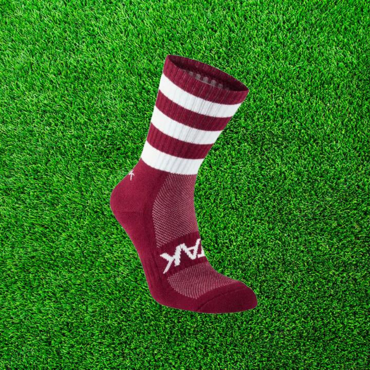 Maroon and white ATAK sock on a green grass background