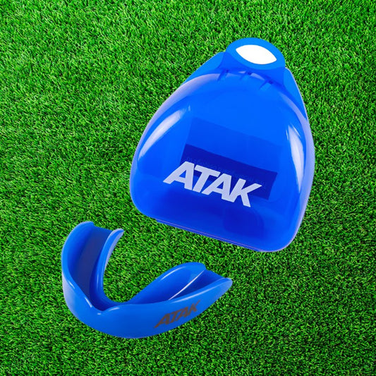 Blue mouthguard with 'ATAK' branding on a green grass background