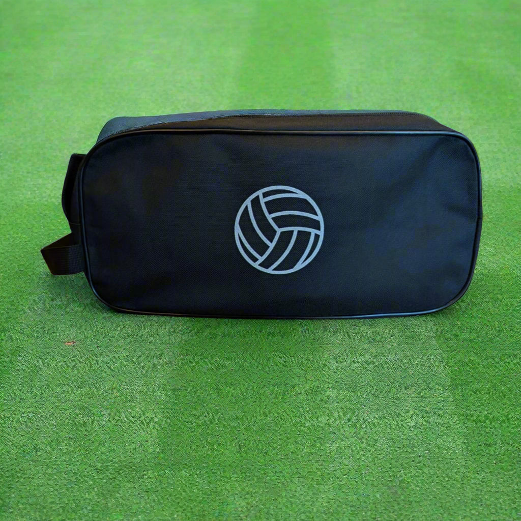 A black boot bag with a football on the back, placed on a green surface.