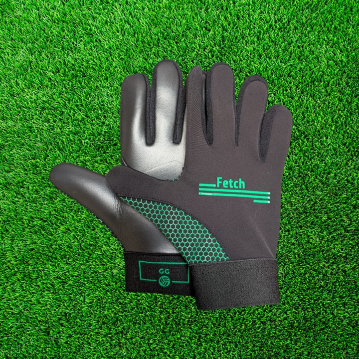 Black and green gloves with green accents on a green grass background