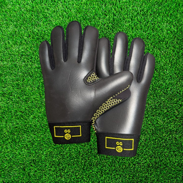 Black and yellow gloves with yellow accents on a green grass background