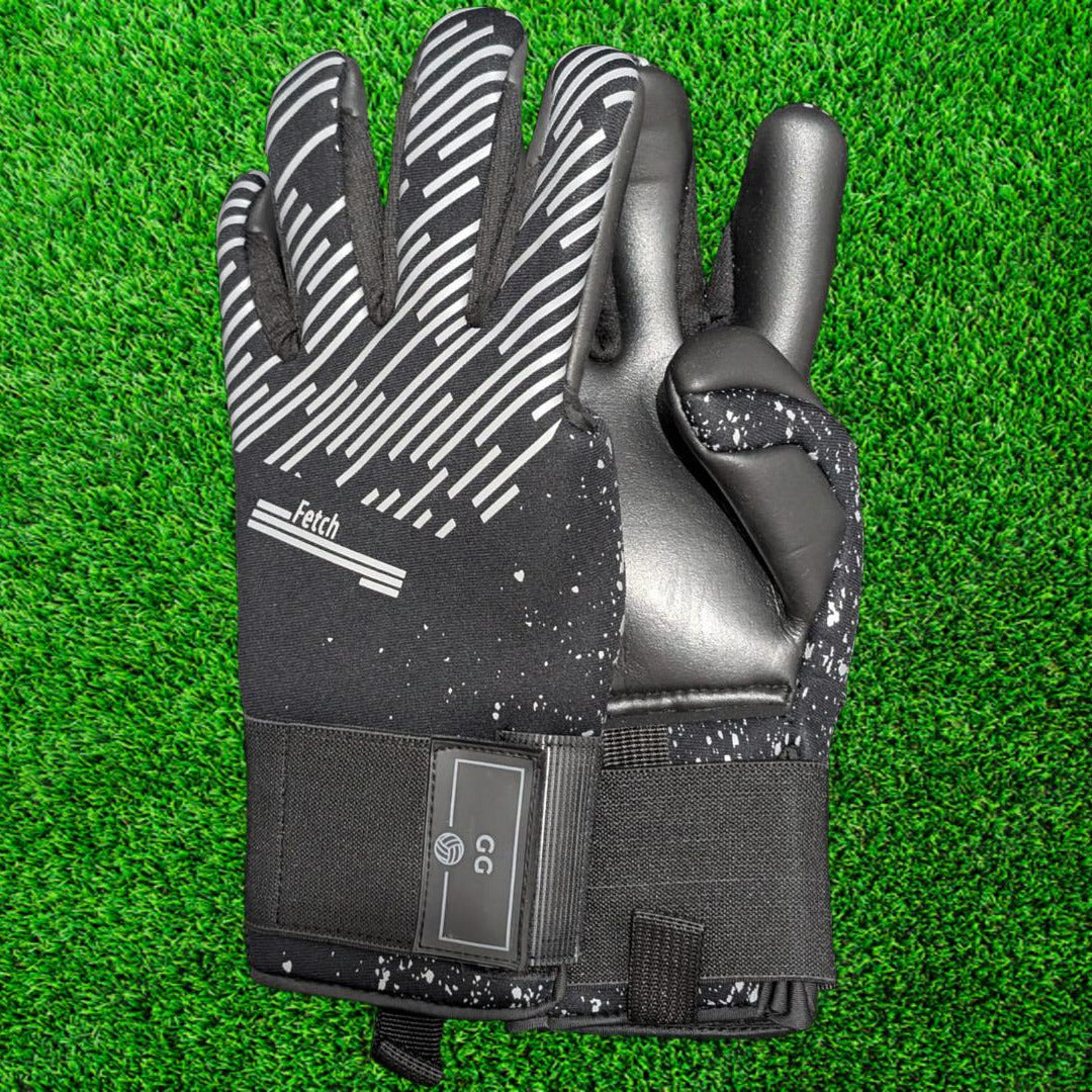 Black and gray goalkeeper glove on a green grass background