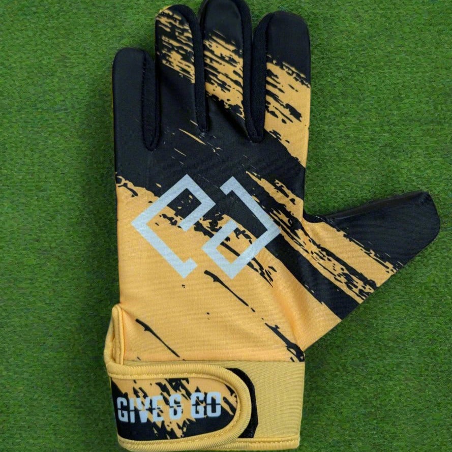 Black and yellow GiveAndGo gloves on a green grass background