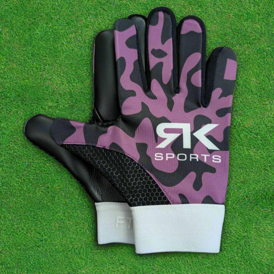 Purple and black RK sports gloves on a green grass background