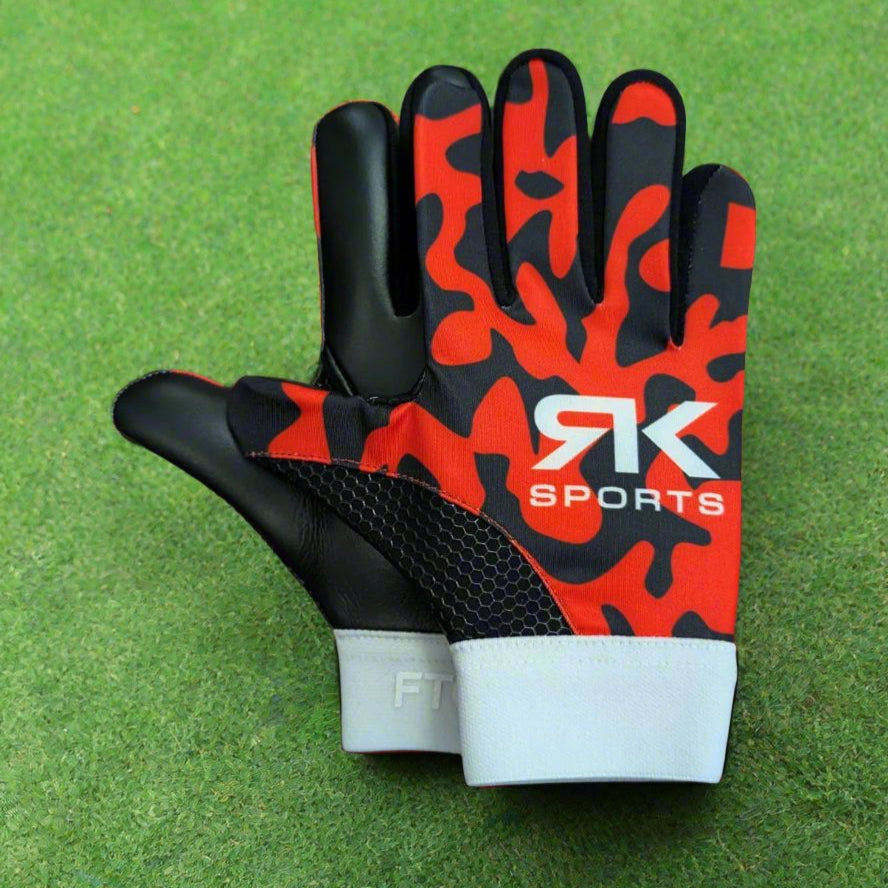 Red and black RK sports gloves on a green grass background