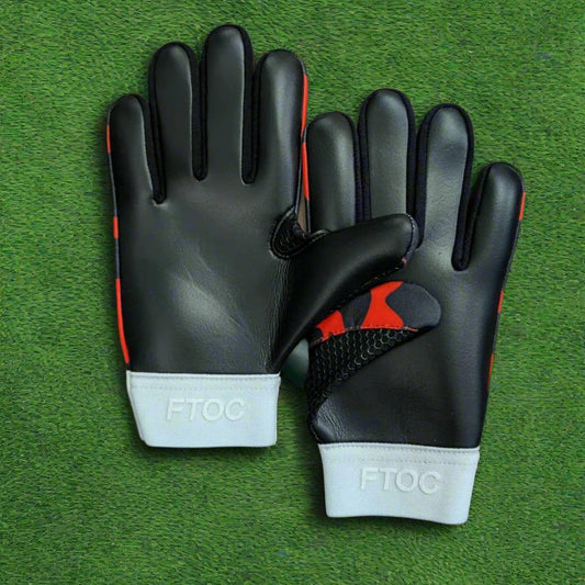 Red and black RK sports gloves on a green grass background