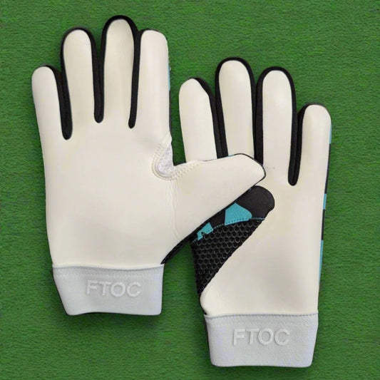Teal and black RK sports gloves on a green grass background