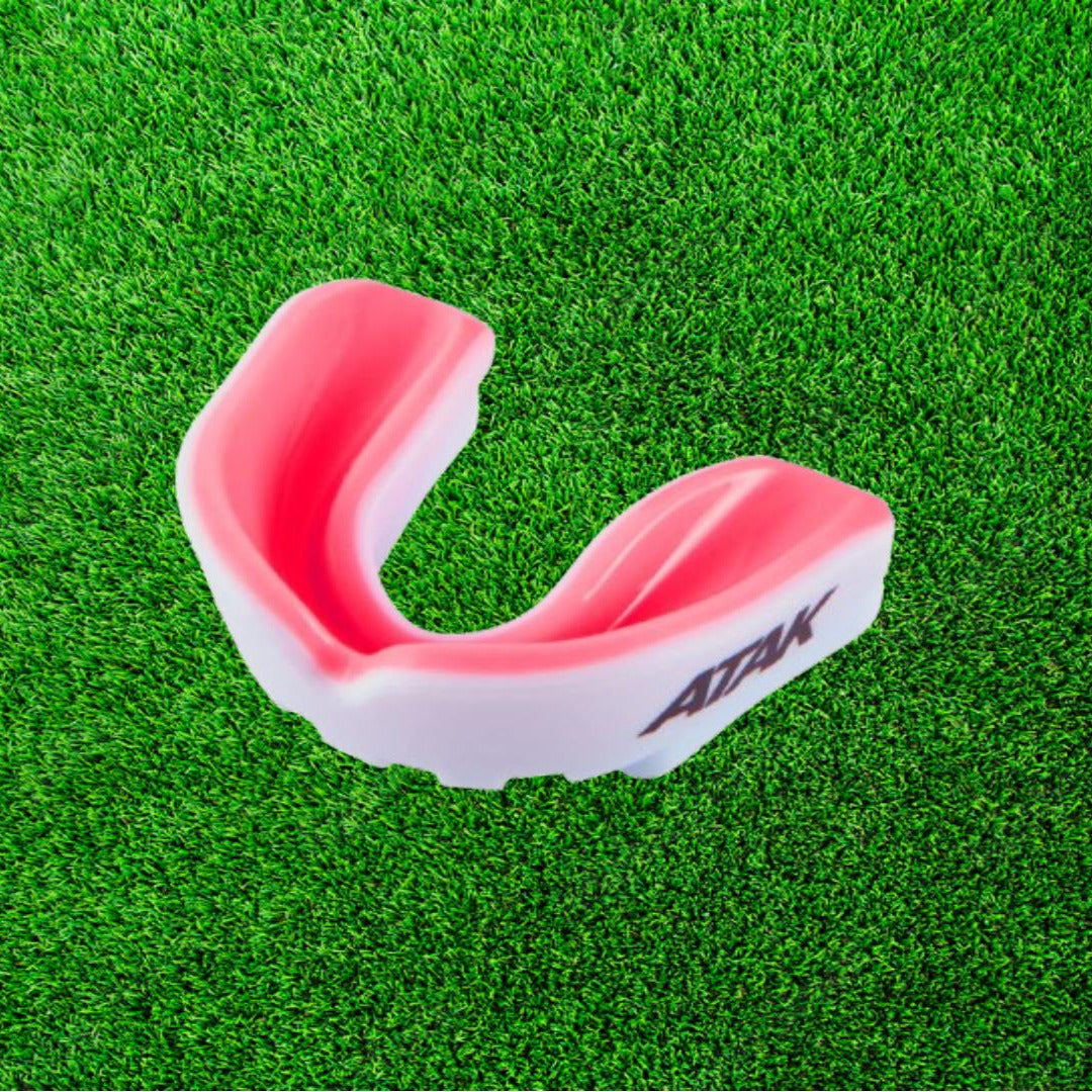 Pink and white mouthguard on a green grass background