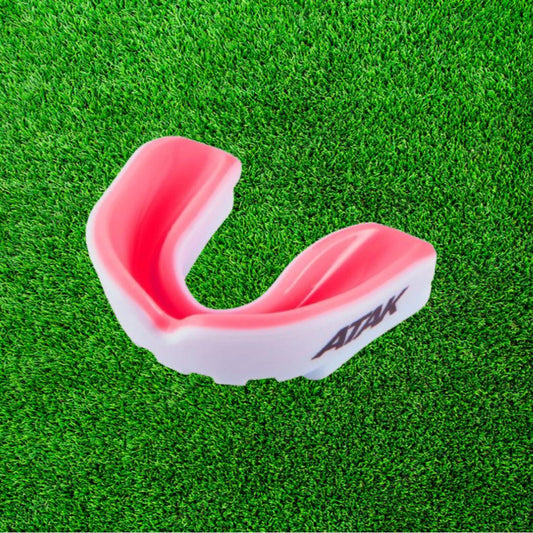 Pink and white mouthguard on a green grass background