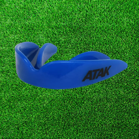 Blue mouthguard with 'ATAK' branding on a green grass background