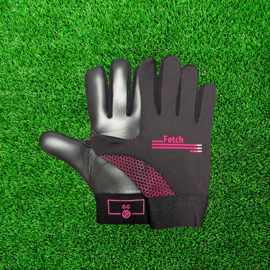 Black and pink gloves with pink accents on a green grass background
