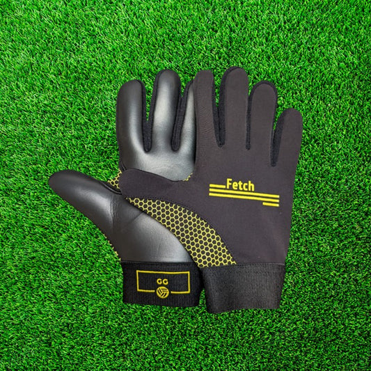 Black and yellow gloves with yellow accents on a green grass background