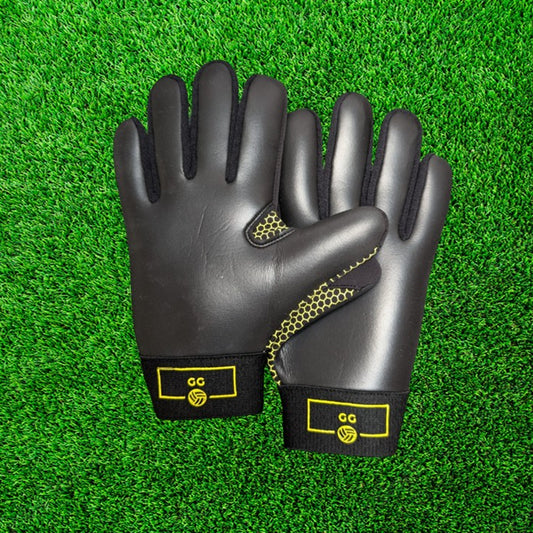 Black and yellow gloves with yellow accents on a green grass background