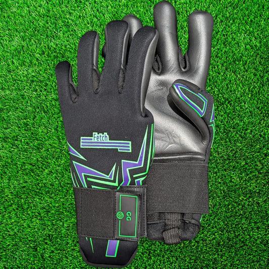 Pair of black goalkeeper gloves with green accents on a green grass background