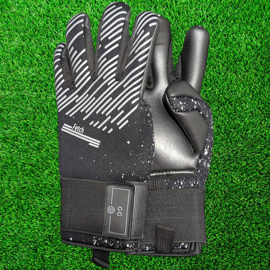Black and gray goalkeeper glove on a green grass background