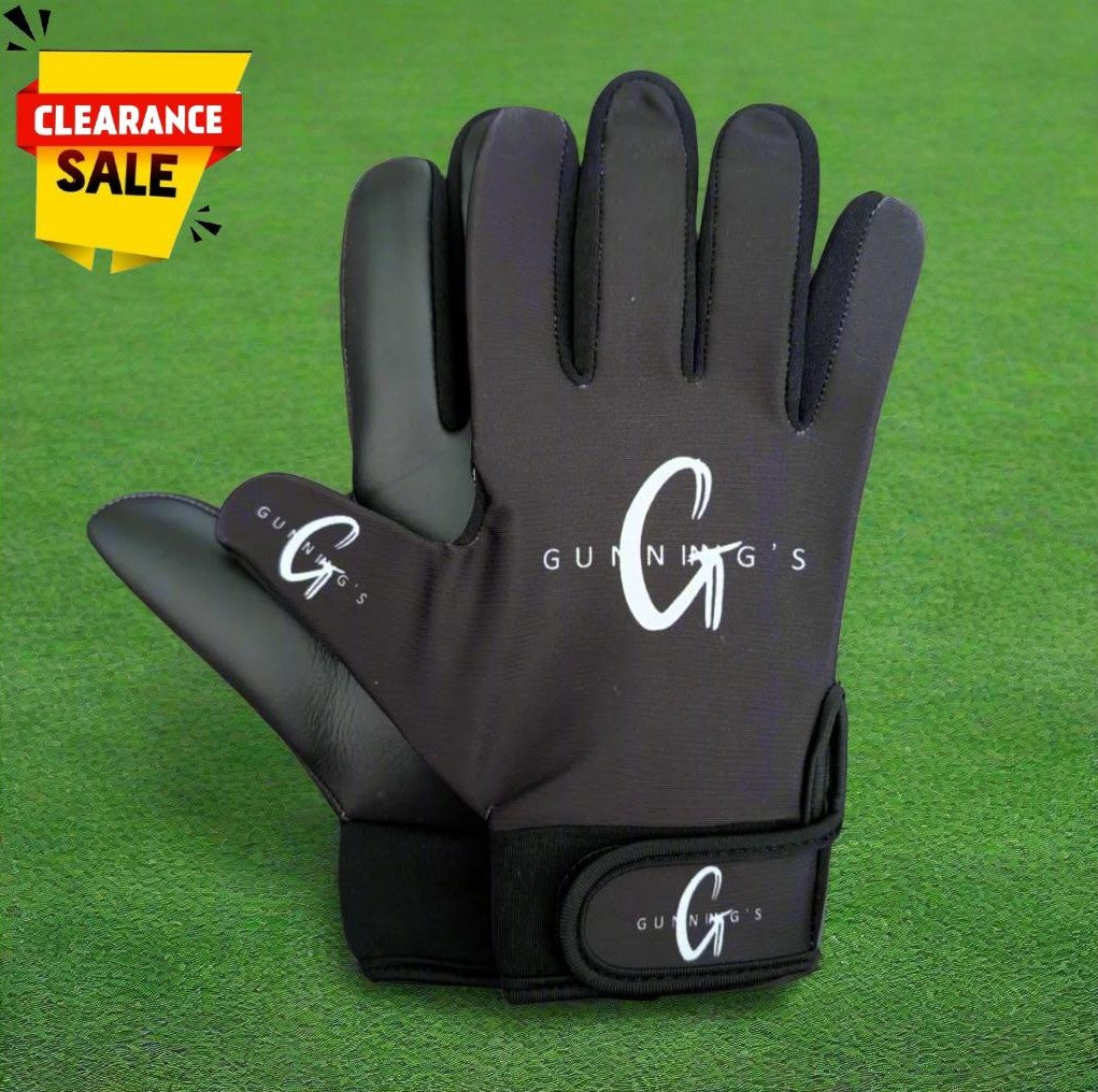 Black and white Gunning's gloves on a green grass background with a clearance sticker
