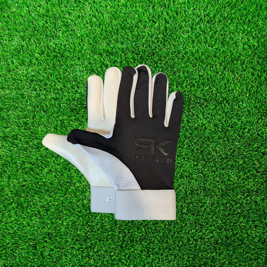 Black and white RK sports gloves on a green grass background