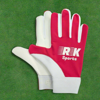 Pink and white RK sports gloves on a green grass background